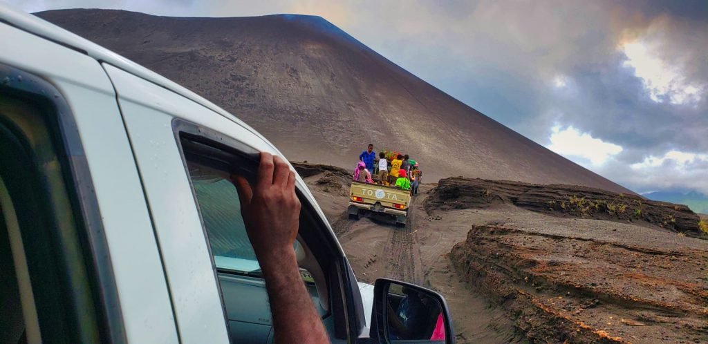 yasur volcano tanna vanuatu black volcanic sand pickup trucks full of people dry river bed